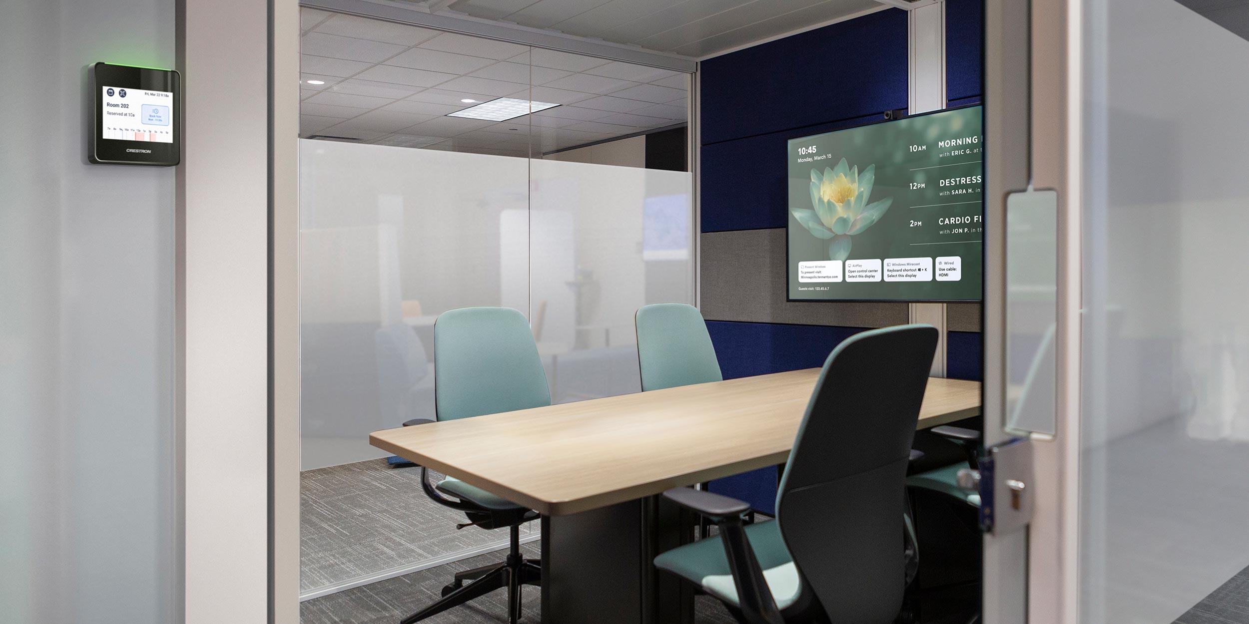 Small conference room with wall-mounted screen and smart room scheduler
