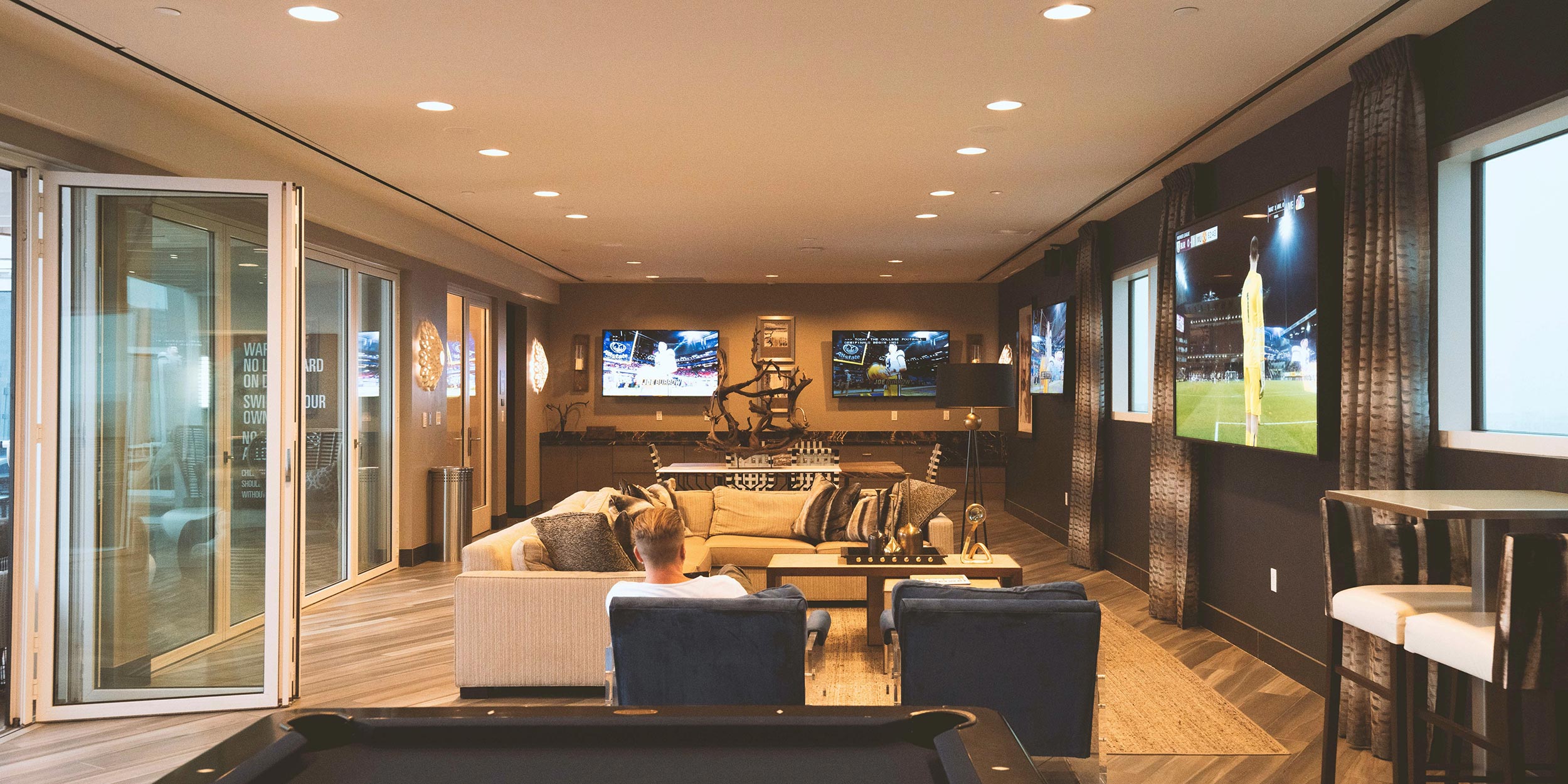 Man watching multiple sports games in a cozy entertainment room with TVs