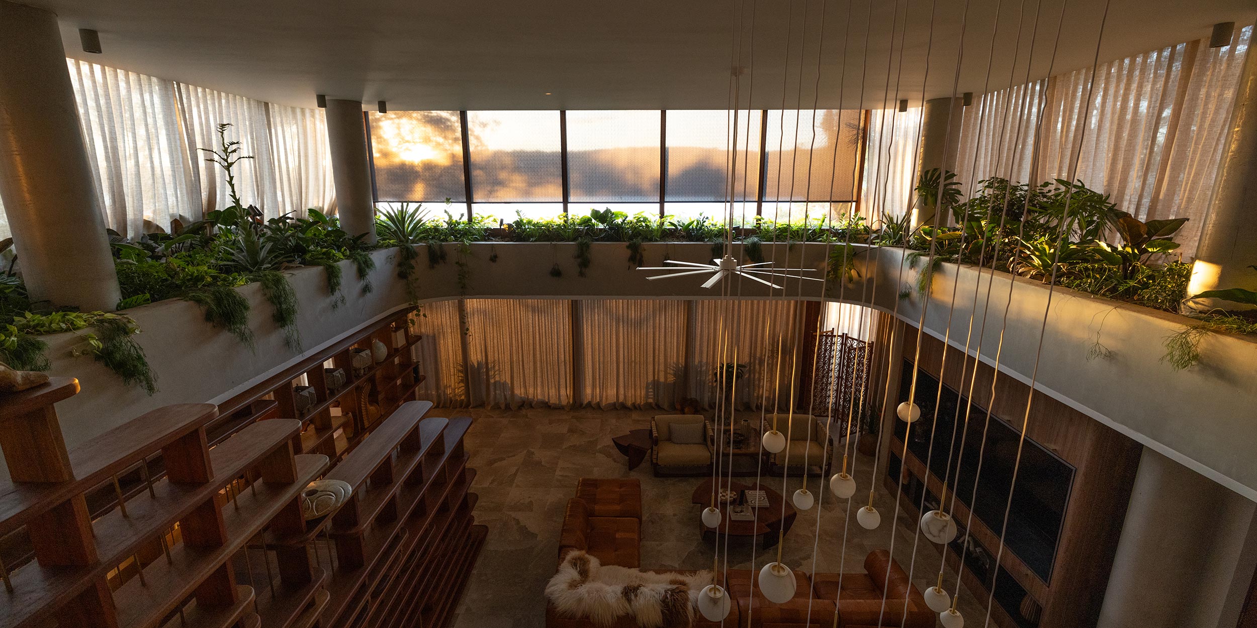 Spacious modern interior with hanging lights and indoor greenery on balcony