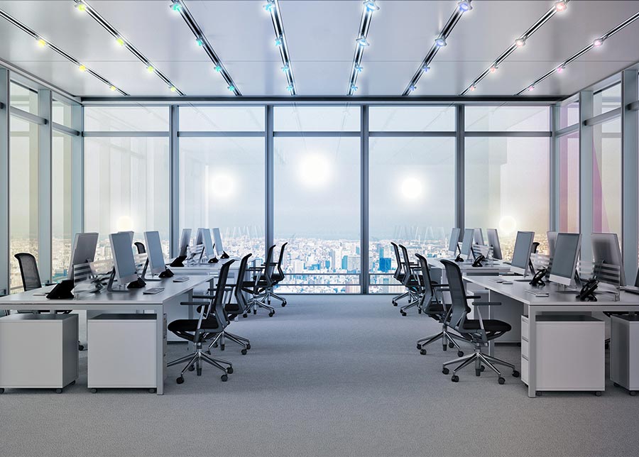 Modern open office space with rows of desks and city view windows