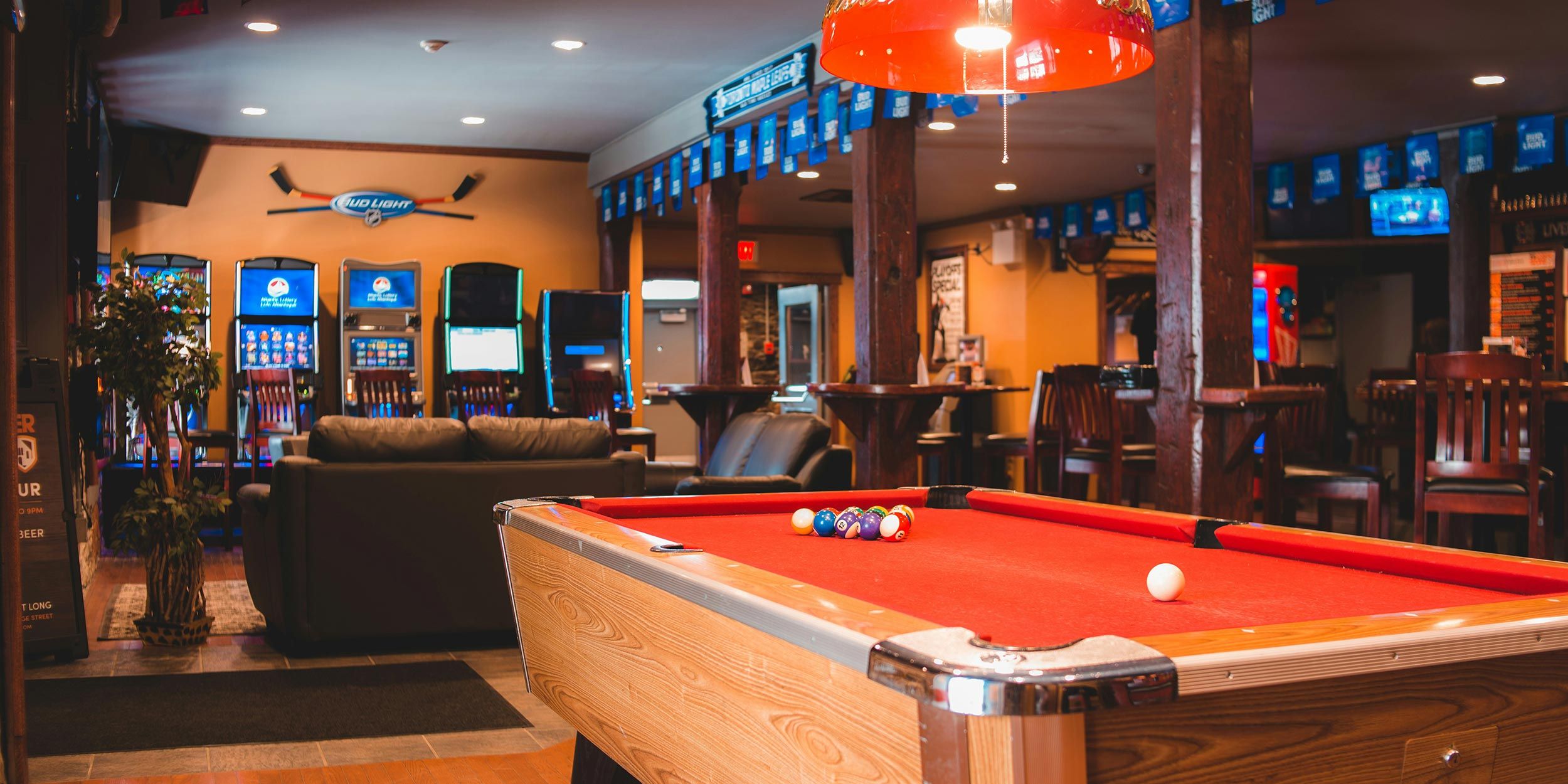 Cozy bar with red pool table, lounge seating, and gaming machines